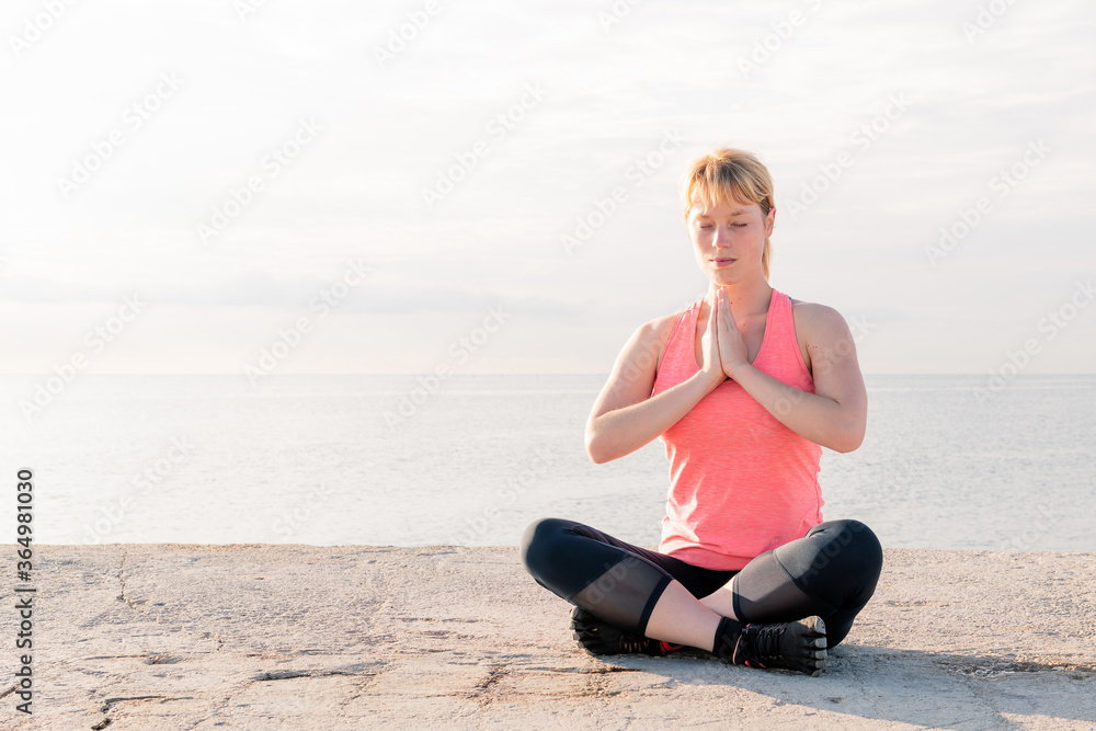 woman practicing yoga sitting in front of the sea