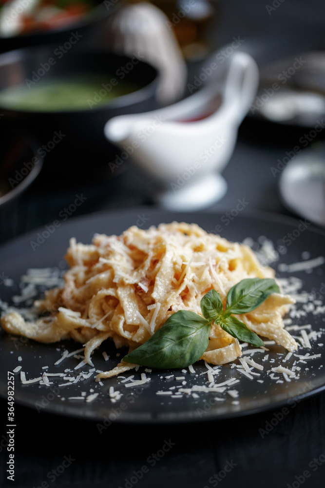 Various culinary dishes on a dark wooden table. Exquisite restaurant serve on dark dishes Various culinary dishes on a dark wooden table. Exquisite restaurant serve on dark dishes