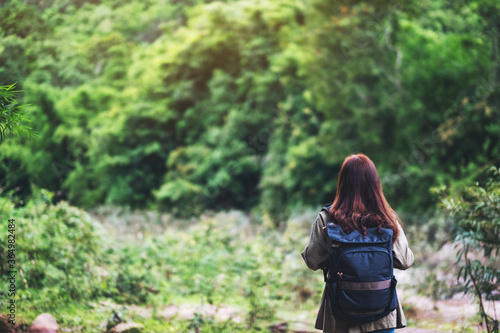 Rear view image of a female traveler with backpack walking by mountain stream for hiking concept