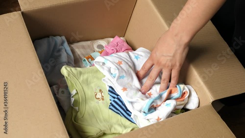 taking checking baby clothes packed in a cardboard box