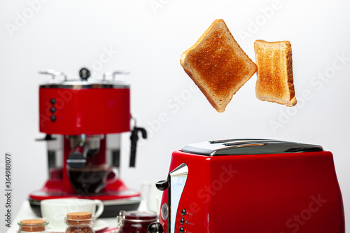 Two toasts jumping out of red toaster against white background
