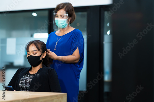 Young Asian woman at hairdresser salon wearing surgical protective face mask. New normal and social distancing concept