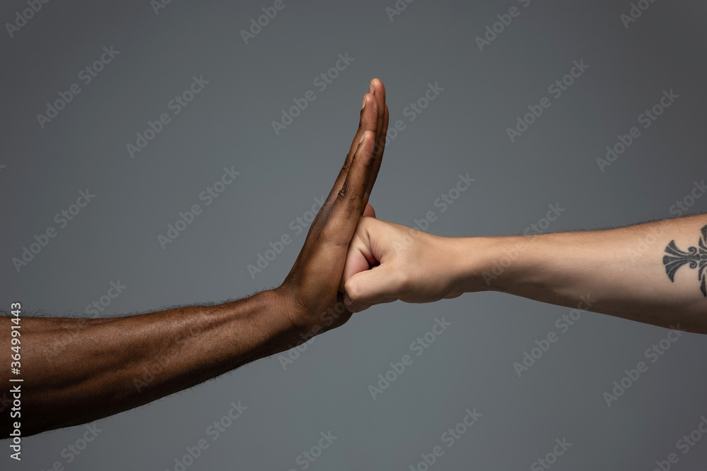 Stop racism. Racial tolerance. Respect social unity. African and caucasian hands gesturing on gray studio background. Human rights, friendship, intenational unity concept. Interracial unity. Stop racism. Racial tolerance. Respect social unity. African and caucasian hands gesturing on gray studio background. Human rights, friendship, intenational unity concept. Interracial unity.