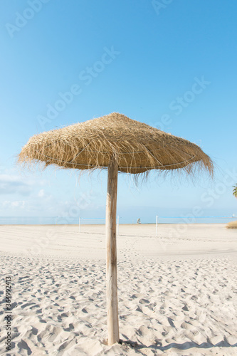 Panoramic view of empty broad beach with white sand blue sea sky straw umbrella volleyball net. Sunny summer day tranquil atmosphere © olindana