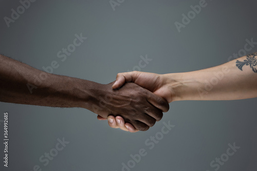 Togetherness. Racial tolerance. Respect social unity. African and caucasian hands gesturing on gray studio background. Human rights, friendship, intenational unity concept. Interracial unity.