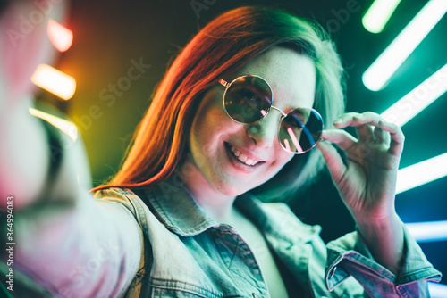  Young woman making selfie at the neon light.