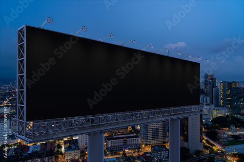 Blank black road billboard with KL cityscape background at night time. Street advertising poster, mock up, 3D rendering. Side view. The concept of marketing communication to promote or sell idea.