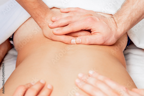 Young man receiving back massage in four hands in spa beauty salon.