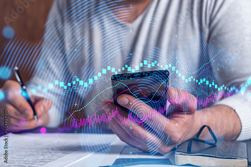 Double exposure of man signing contract with phone and forex graph hologram. Concept of financial market, stock exchange, investment in bonds. photo