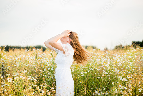 Happy girl on the camomile field, summer sunset. in a white dress. running and spinning, the wind in my hair, life style. freedom concept and hot summer