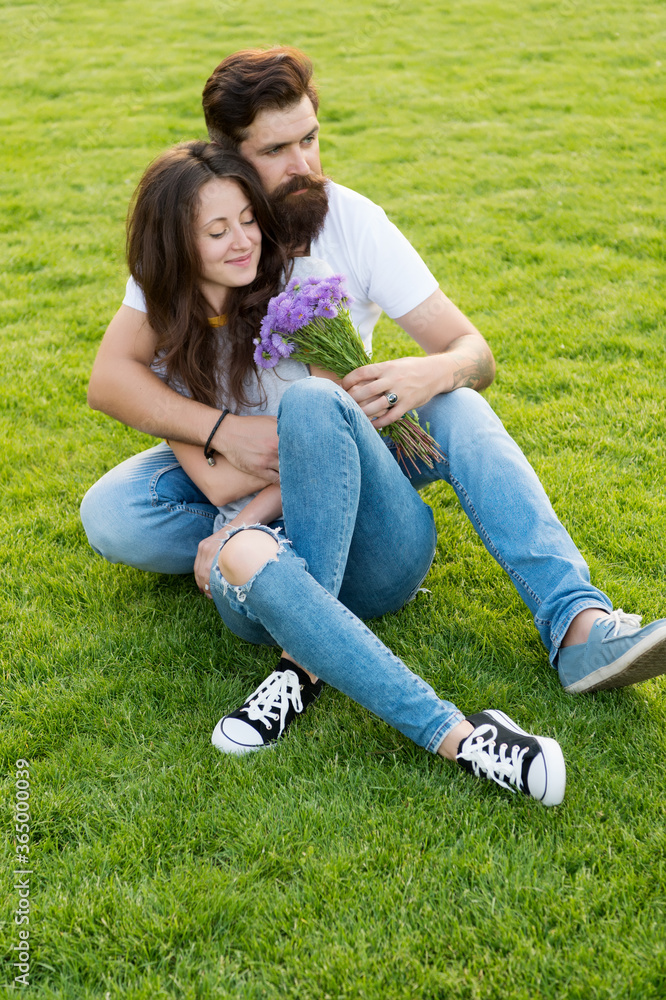 Flowers brighten day. Bearded man give flowers to sexy woman. Couple in love relax on green grass. Flower shop. Holiday celebration. Summer vacation. Flowers and natural gifts Flowers brighten day. Bearded man give flowers to sexy woman. Couple in love relax on green grass. Flower shop. Holiday celebration. Summer vacation. Flowers and natural gifts