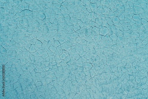 Texture of blue painted wall with cracks in the paint