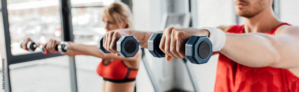 panoramic concept of sport couple exercising with dumbbells in gym