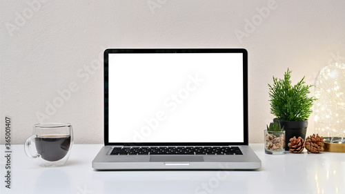 Mock up modern workspace with laptop, coffee cup, light bulb and blank screen laptop on white background. Front view