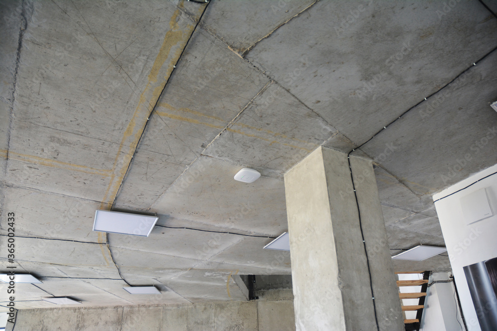 Modern square ceiling lighting and wiring installation on the ceiling and along concrete column during renovation in a new apartment. Modern square ceiling lighting and wiring installation on the ceiling and along concrete column during renovation in a new apartment.