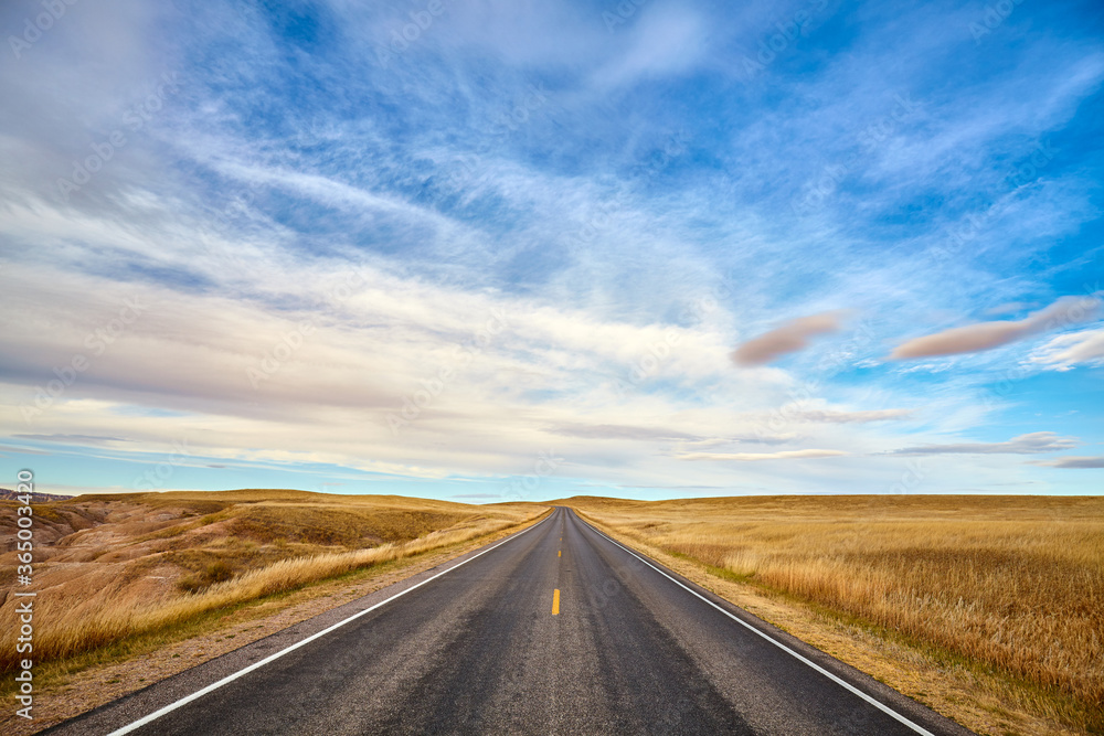 Scenic road in Badlands National Park at sunset, travel concept, USA.