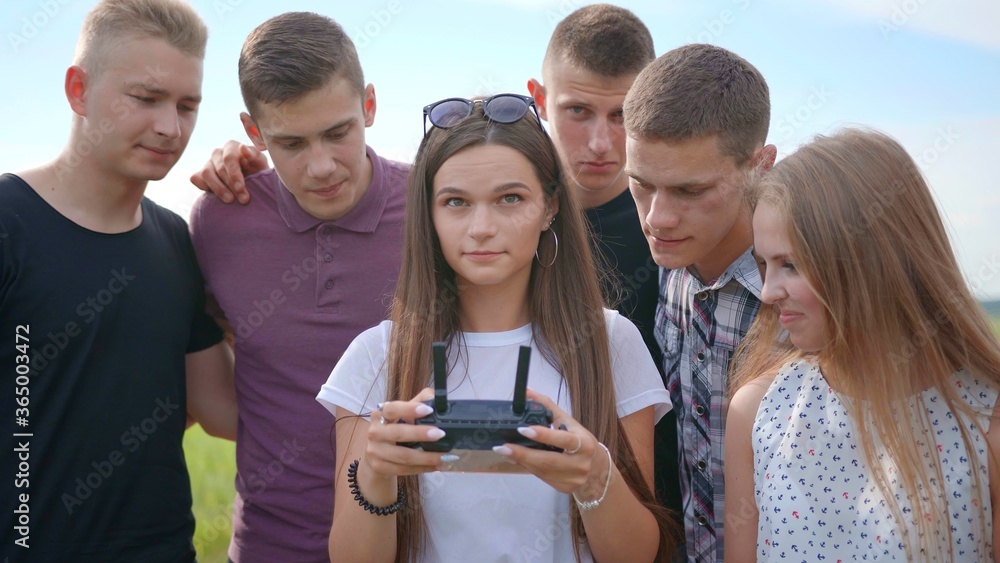 Cheerful friends control the drone using the remote control. Cheerful friends control the drone using the remote control.