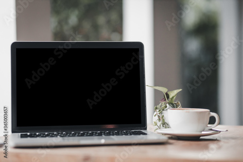 Mockup of laptop computer with empty screen with coffee cup on table of the coffee shop background,Black screen