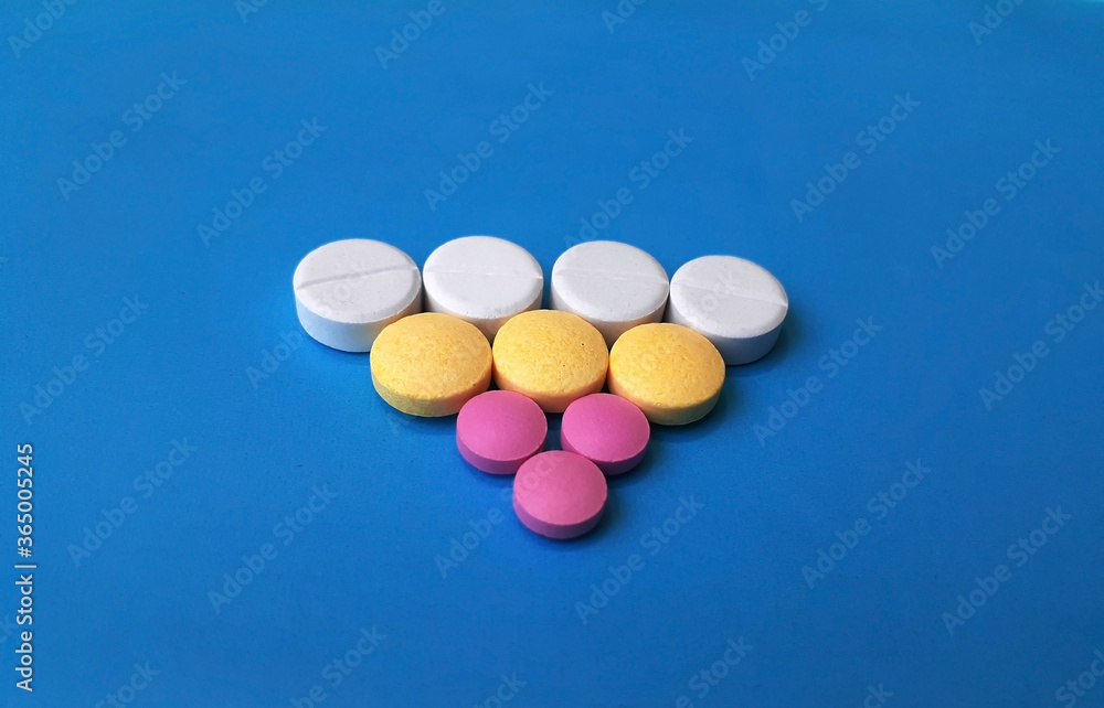 Assortative triangular pattern of med pills and capsules, isolated on blue, mixed pharmaceutical tablets. Assortative triangular pattern of med pills and capsules, isolated on blue, mixed pharmaceutical tablets.