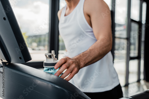 cropped view of sportsman touching sports bottle in gym