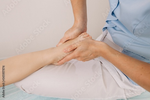 An osteopath does a foot massage to a child. Correction of the legs in the direction of a pediatrician.
