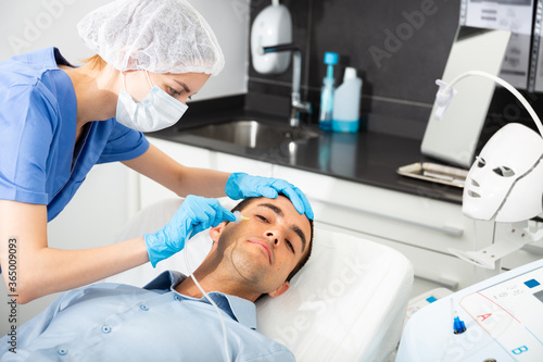 Young man patient receiving anti-aging injections carboxytherapy procedure in beautician office of aesthetic clinic