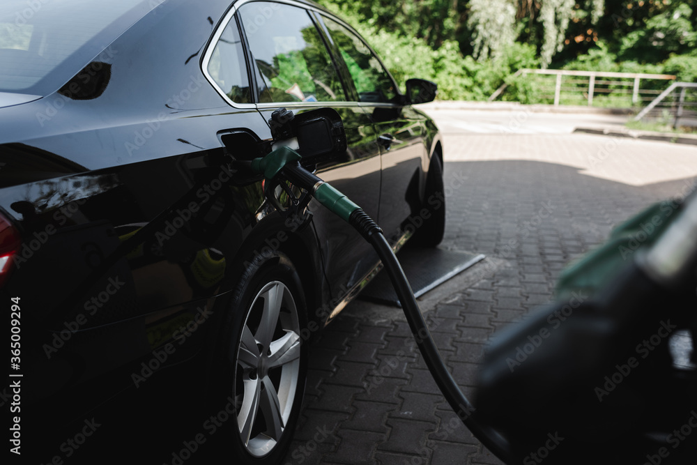 Selective focus of fueling nozzle in open gas tank of auto on gas station Selective focus of fueling nozzle in open gas tank of auto on gas station