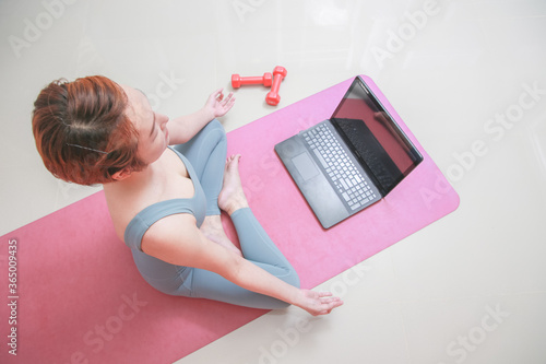 Closeup young sporty woman do practice video online training hatha yoga Sukhasana posture relax.