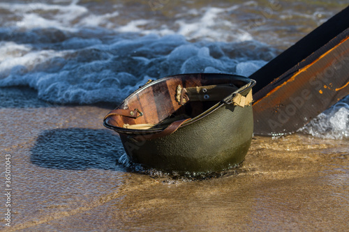 Wet Amcerian WW2 M1 helmet left behind on the  beach.  D-Day reenactment event day. Hel, Poland 
 photo