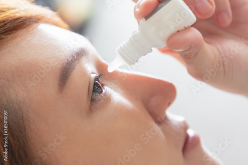 Closeup view of young asian woman applying eye drop. artificial tears.