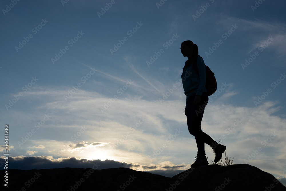 Young Woman Traveler Hiking with Backpack on the Beautiful Rocky Trail at Summer Sunset. Travel and Adventure Concept.