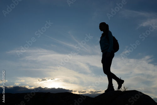 Young Woman Traveler Hiking with Backpack on the Beautiful Rocky Trail at Summer Sunset. Travel and Adventure Concept.