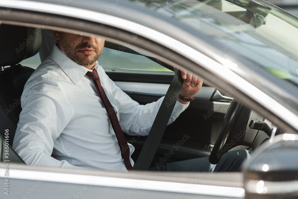 Selective focus of businessman holding seat belt in car