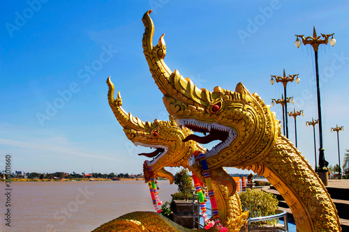 Golden nagas statues near the mekong under blue sky