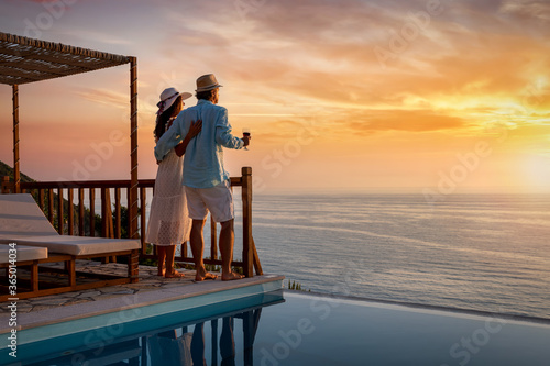 Schilderij op canvas Ein Paar im Urlaub genießt den romantischen Sonnenuntergang über dem Meer bei ei