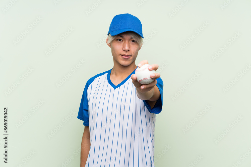 Young asian man playing baseball over isolated green background Young asian man playing baseball over isolated green background