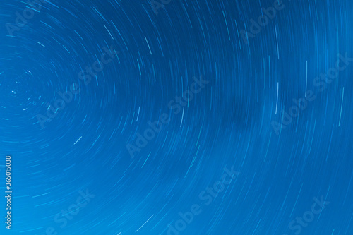 Background of round or circular star track or trajectory on the blue clear night sky. Symbol of space, cosmos, expanse infinity and universe