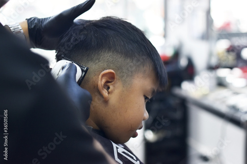 young businessman looking at the camera. An Asian boy is sitting in a barber shop.