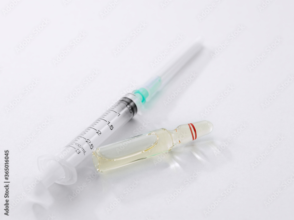 Close up view of the ampule with medicine and syringe on white back Close up view of the ampule with medicine and syringe on white back