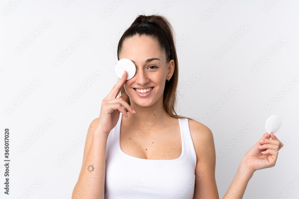 Young brunette woman over isolated white background with cotton pad for removing makeup from her face and smiling Young brunette woman over isolated white background with cotton pad for removing makeup from her face and smiling