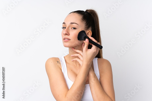 Young brunette woman over isolated white background holding makeup brush
