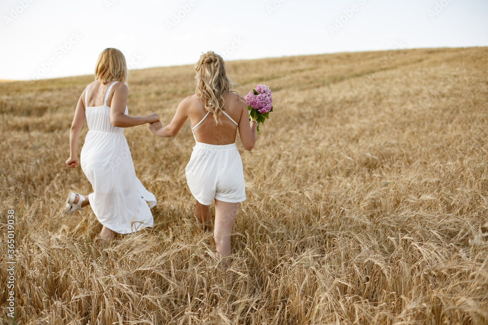 Adult mother with daughter. Beautiful girl in a white dress. Family in a summer field Adult mother with daughter. Beautiful girl in a white dress. Family in a summer field