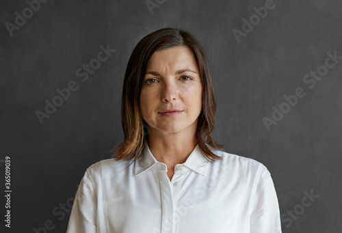 Businesswoman standing confidently in front of a blank chalkboard © mavoimages