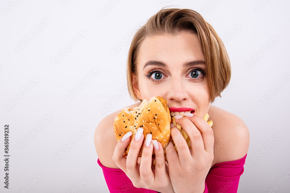girl eats with appetite, overweight from fast food, hamburger and french fries in hands, beautiful young girl with  bright appearance, burger girl
