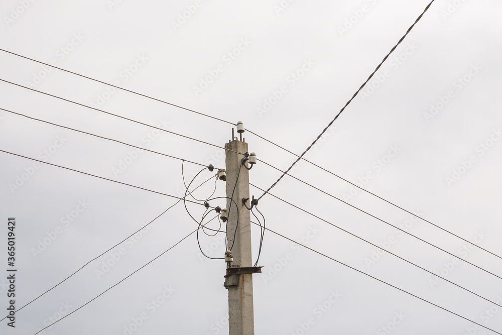 Fototapeta premium Electricity pole with power wires line in a cloudy day