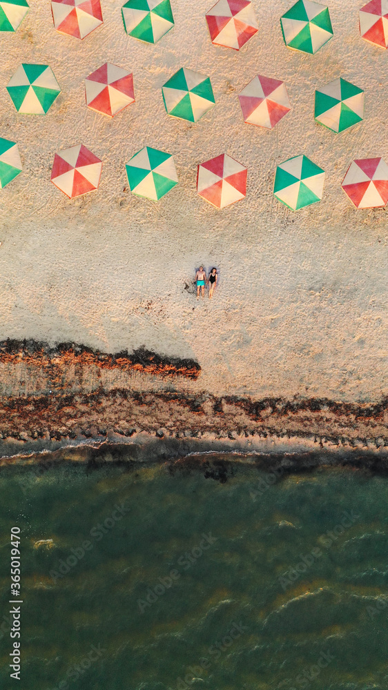 young couple is lying on a tropical sandy beach near the ocean. Aerial view on attractive couple relaxing on sandy beach, tropical vacation. Top view from drone. aerial view.