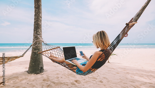 Fotografía Young woman tourist reading notification on smartphone in roaming while lying on