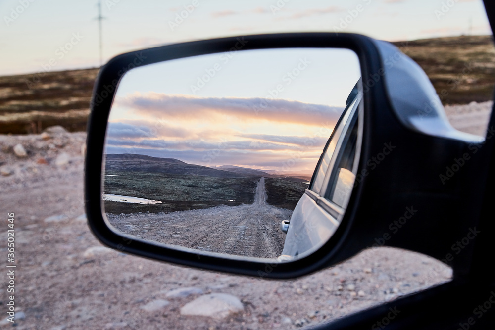 Car Mirror and reflection of the road and sky in it.
