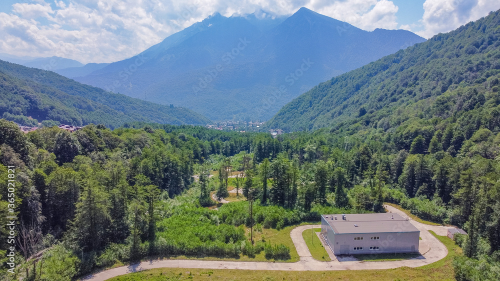 Fototapeta premium Infrastructure of a modern city. Aerial view of beautiful futuristic modern water intake pumping wells against the background of mountains and peaks. Sochi, Russia.