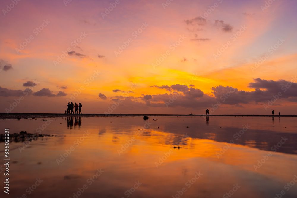 Burning bright sky during sunset on a tropical beach. Sunset during the exodus, the strength of people walking on water Burning bright sky during sunset on a tropical beach. Sunset during the exodus, the strength of people walking on water